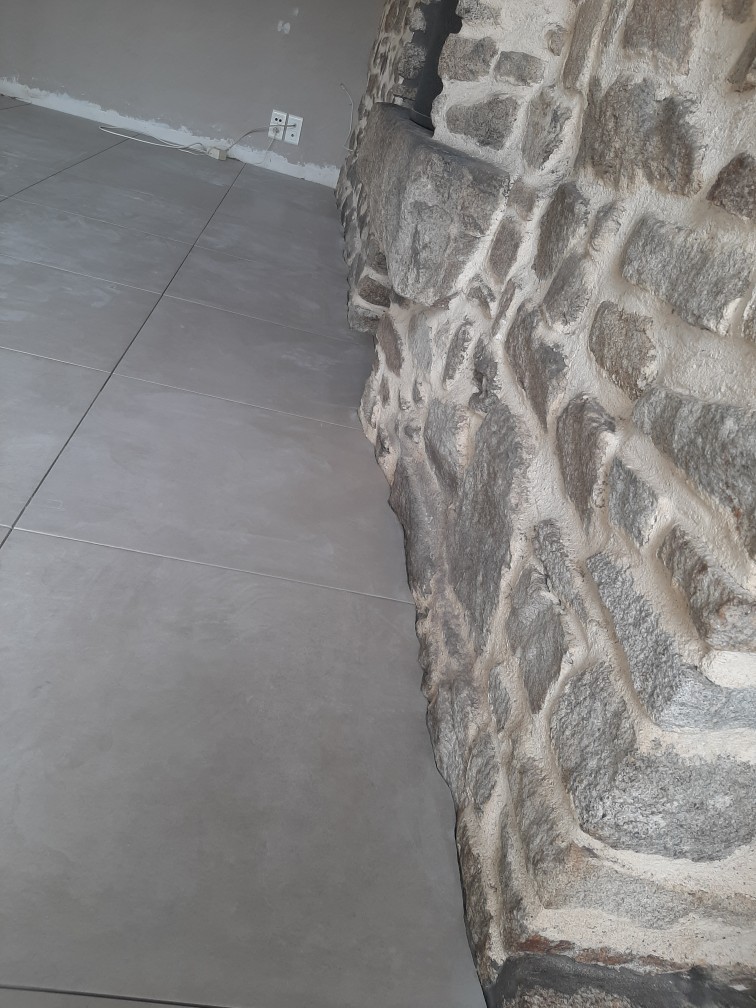 Pose et découpe de carrelage sol avec mur en pierre