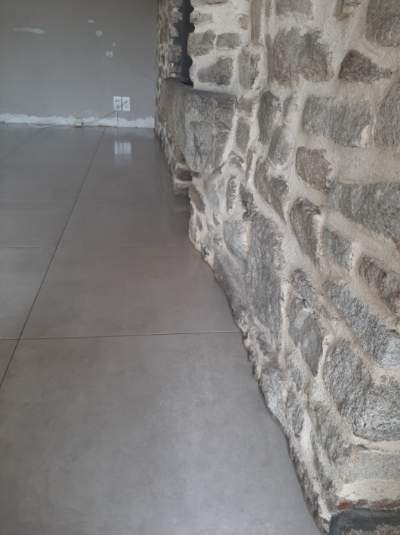 Pose et découpe de carrelage sol avec mur en pierre